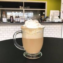 A latte topped with whipped cream in a glass mug at J316.